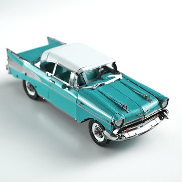 Ervaar de Americana van de jaren 50 met het 1957 Chevy metalen bouwpakket van SlimSpul nederland b.v. - een gedetailleerd frontmodel in klassiek turquoise en wit, met chromen accenten en whitewall banden tegen een effen achtergrond.