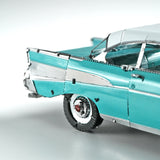 Close-up van een gedetailleerd 1957 Chevy metalen bouwpakket van SlimSpul nederland b.v., met de nadruk op het turquoise en zilveren achterspatbord, de staartvin, het wiel en het dak - een iconisch klassiek automodel - tegen een effen lichte achtergrond.