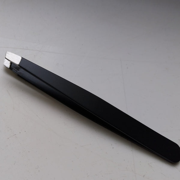 Een zwart pincet met schuine punt uit SlimSpul nederland b.v.'s Diverse gereedschap voor de metalen bouwpakketten (geen set) ligt op een wit oppervlak, ideaal voor het assembleren van metalen bouwpakketten.