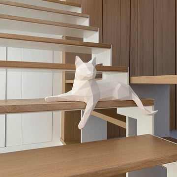Witte liggende kat met één hangend voorpootje als 3D papiermodel op een plankrand