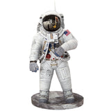 Een figuur van een Apollo 11 astronaut in een wit pak met een reflecterende helm staat op een grijze basis. Het is geïnspireerd op het SlimSpul "Apollo 11 astronaut - metalen bouwpakket" en heeft een patch met de Amerikaanse vlag en gedetailleerde uitrusting en slangen.