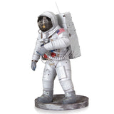 Het SlimSpul Apollo 11 astronaut - metalen bouwpakket heeft een realistisch figuur in een wit ruimtepak met helm, rugzak en Amerikaanse vlag patch, staande op een grijze rotsachtige basis-een perfect maanlanding model voor verzamelaars.