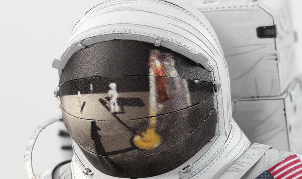 Een close-up van het SlimSpul Apollo 11 astronaut - metalen bouwpakket helmvizier, dat een maangolfscène met een vlag en bal weerspiegelt - een opvallend eerbetoon aan dit historische model.