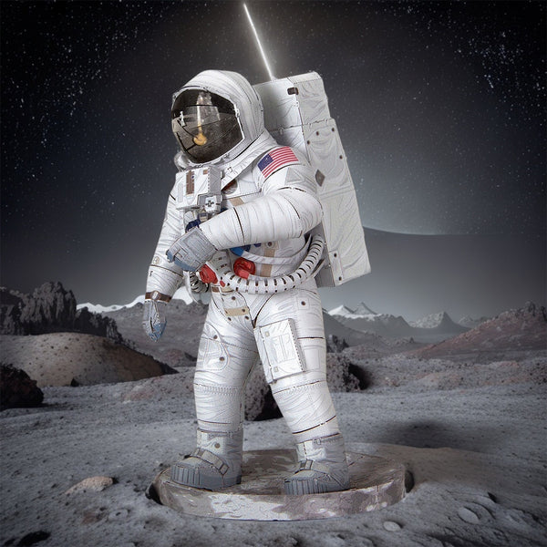 Een Apollo 11 astronaut in een wit ruimtepak staat op het rotsachtige oppervlak van de maan met daarachter bergen en een planeet - net als het in elkaar zetten van het SlimSpul Apollo 11 astronaut - metalen bouwpakket van de historische maanlanding.