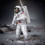 Een Apollo 11 astronaut in een wit ruimtepak staat op het rotsachtige oppervlak van de maan met daarachter bergen en een planeet - net als het in elkaar zetten van het SlimSpul Apollo 11 astronaut - metalen bouwpakket van de historische maanlanding.