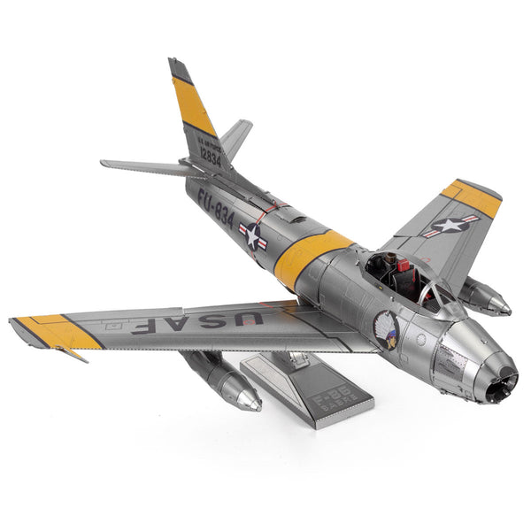 Het F-86 Sabre metalen bouwpakket van SlimSpul nederland b.v. is een zilverkleurig model vliegtuig met gele strepen, U.S. Air Force markeringen, raketten onder de vleugels, een open gedetailleerde cockpit en inclusief displaystandaard.
