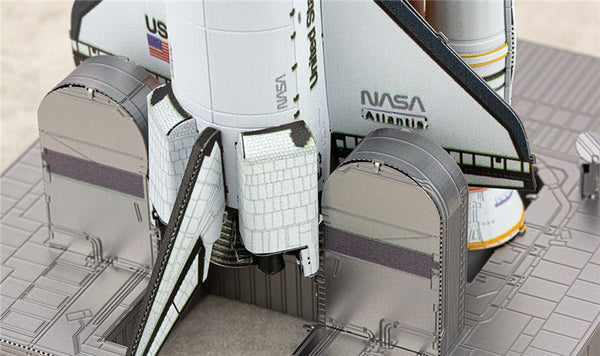 Close-up van het Space Shuttle Metalen Bouwpakket - Iconisch Ruimtevaartuig Model van SlimSpul nederland b.v. op het lanceerplatform, met gedetailleerde shuttle tegels, Amerikaanse vlag, NASA logo, raketboosters en een deel van de brandstoftank.