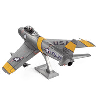 Het F-86 Sabre metalen bouwpakket van SlimSpul nederland b.v. is een zilveren modelstraaljager met gele en zwarte details, USAF-embleem, staartnummer 12834 en FU-834 op de romp, geïnspireerd door de Koreaanse Oorlog. Wordt geleverd met standaard.