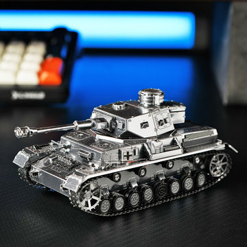 Het Panzer IV tank metalen bouwpakket van SlimSpul nederland b.v. is een gedetailleerd zilverkleurig model dat op een donker oppervlak staat, met een vervaagd toetsenbord en blauwe achtergrondverlichting op de achtergrond.