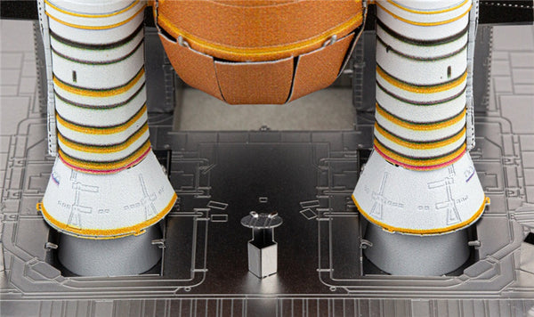 Close-up van het Space Shuttle Metalen Bouwpakket - Iconisch Ruimtevaartuig Model van SlimSpul nederland b.v., met gedetailleerde raketboosters met gekleurde banden op een grijs platform - ideaal voor elke metalen bouwpakket fan.