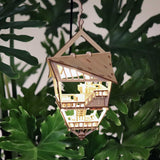 De Sky Lodge van Tiny Treehouses Europe is een klein, gedetailleerd DIY houten modelbouwpakket van een boomtop lodge ornament, van binnen verlicht door LED-lampjes, hangend tussen grote groene bladeren.