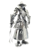 Het Imperial Guard Ming Dynasty Metalen Bouwpakket van SlimSpul nederland b.v. heeft een gedetailleerde Chinese krijgerfiguur in sierlijke traditionele wapenuitrusting, die een lintachtig voorwerp vasthoudt, weergegeven op een witte achtergrond.