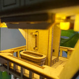 Een close-up van het Sky Lodge bouwpakket van Tiny Treehouses Europe laat een miniatuurbalkon zien met een bad, een reling en oplichtende LED-lampjes, die de gezellige charme van een boomtopverblijf oproepen.