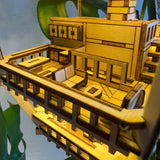 Een close-up van het Sky Lodge DIY houten modelbouwpakket van Tiny Treehouses Europe, met geometrische vormen en open ruimtes, tegen weelderige groene planten op de achtergrond.