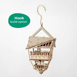 De Tiny Treehouses Europe Sky Lodge is een houten bouwpakket van een boomhut met een schuin dak, balkons en een ophanghaak. Een groen "Haak bouw optie" label verschijnt. De achtergrond is wit.