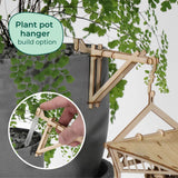 De Sky Lodge van Tiny Treehouses Europe is een houten bouwpakket waarmee je een plantenpothanger kunt maken. Afgebeeld is de Sky Lodge bevestigd aan een grijze plantenbak met varens. Een inzet toont de installatie met gereedschap. Tekst: Plant pot hanger bouw optie.