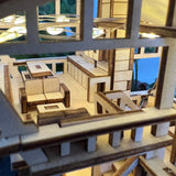 Een close-up van Tiny Treehouses Europe's Tropical Lookout, een gedetailleerd doe-het-zelf houten modelbouwpakket dat het interieur van een modern huis laat zien met keukenkastjes, een eettafel met banken en kleine ramen - allemaal gemaakt van licht hout.