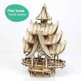 De Temple of Joy van Tiny Treehouses Europe is een klein doe-het-zelf houten modelbouwpakket van een gebouw in pagode-stijl met meerdere gebogen, gelaagde daken en ingewikkelde uitgesneden details. Een groene cirkel wijst op de "Flat base build option".