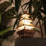 De Tempel van Sereniteit van Tiny Treehouses Europe is een klein, verlicht houten bouwpakket dat lijkt op een pagode, genesteld tussen groene bladeren om een warme gloed te werpen en een gezellige, rustige sfeer te creëren.