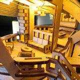 Een close-up van Horizons Edge van Tiny Treehouses Europe-een gedetailleerd zelfgemaakt houten modelbouwpakket van een moderne woonkamer met miniatuurmeubels, trappen, leuningen en warme verlichting die het gezellige interieur verlicht.
