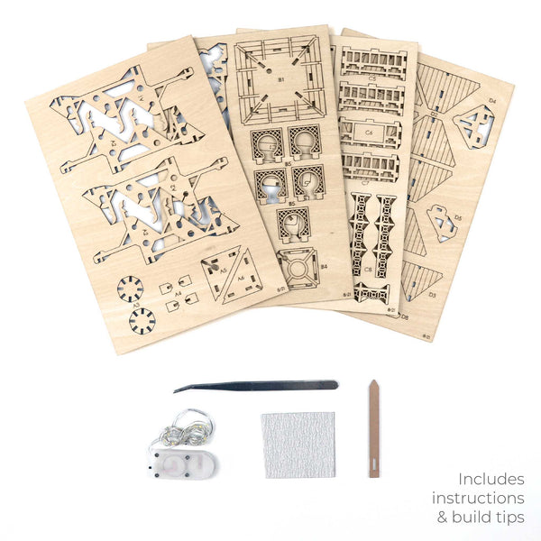Vijf lasergesneden houten platen voor de Tempel van Sereniteit van Tiny Treehouses Europe worden getoond met doe-het-zelf-assemblagegereedschap: een pincet, schuurpapier, een sleutelring, wit licht en een stok. De tekst luidt: Inclusief instructies & bouwtips.