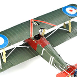 Close-up van het Sopwith Camel jachtvliegtuig metalen bouwpakket van SlimSpul nederland b.v., met groene vleugels, een rode romp en blauw-wit-rode rondellen, gedetailleerde cockpit en tuigage als een Eerste Wereldoorlog jachtvliegtuig.