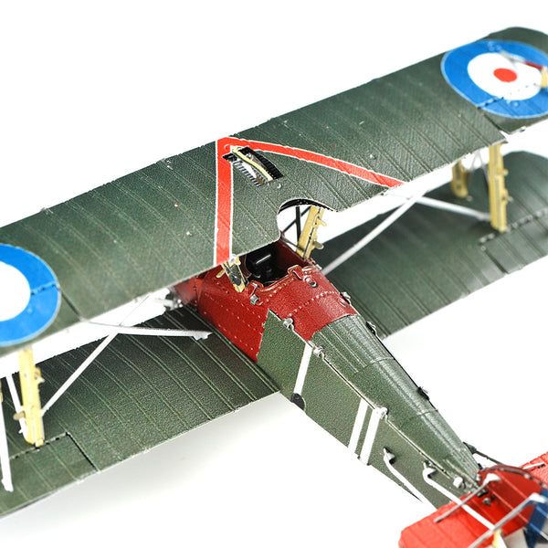 Close-up van het Sopwith Camel jachtvliegtuig metalen bouwpakket van SlimSpul nederland b.v., met groene vleugels, een rode romp en blauw-wit-rode rondellen, gedetailleerde cockpit en tuigage als een Eerste Wereldoorlog jachtvliegtuig.