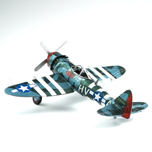 Een P-47 Thunderbolt metalen bouwpakket van SlimSpul nederland b.v., een miniatuur WOII jachtvliegtuig met blauwe en groene camouflage, witte strepen en U.S. Air Force insignes op vleugels en staart, gefotografeerd op een witte achtergrond.