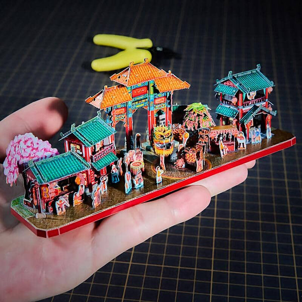 Chinees straatfestival metalen diorama op een hand als schaalreferentie met tempelpoorten en optocht