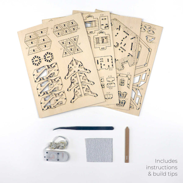 Vier lasergesneden houten platen, een metalen gereedschap, schuurpapier, bruine stok, draad, batterij en LED-lampjes voor de Woodland Outpost van Tiny Treehouses Europe worden getoond. Tekst: "DIY houten modelbouwpakket met instructies & bouwtips.