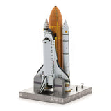 Het Space Shuttle Metalen Bouwpakket van SlimSpul nederland b.v. is een iconisch model met twee solid rocket boosters en een externe tank, weergegeven op een lanceerplatform tegen een witte achtergrond.
