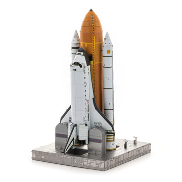 Het Space Shuttle Metalen Bouwpakket van SlimSpul nederland b.v. is een iconisch model met twee solid rocket boosters en een externe tank, weergegeven op een lanceerplatform tegen een witte achtergrond.