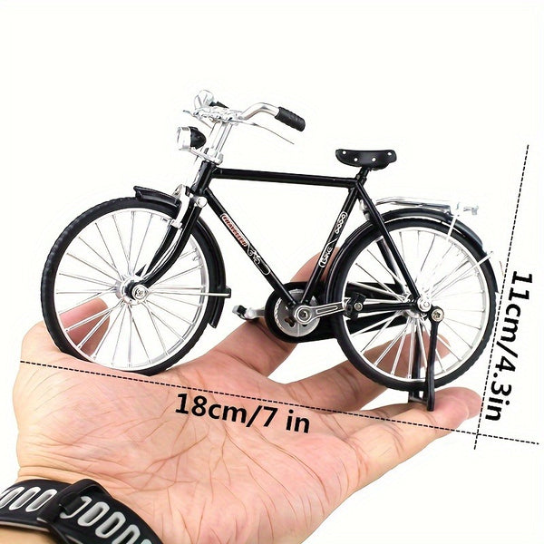Iemand houdt het Stadsfiets Metalen Bouwpakket (1:8, Zwart of Groen) van SlimSpul nederland b.v. vast; het klassieke fietsmodel is 18 cm lang en 11 cm hoog met zichtbaar gedetailleerd stuur, wielen en zadel.