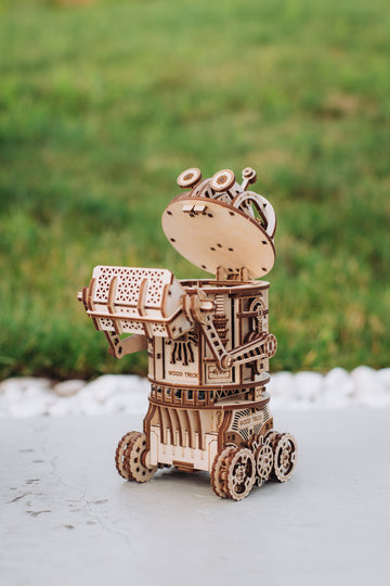 WoodTrick Space Junk Robot met opgeheven opvangbak en open kop op zijn vier houten wielen