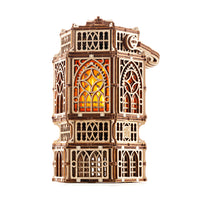 The WoodTrick Antique Lantern - Houten bouwpakket voor volwassenen van WoodTrick is een gedetailleerd houten lantaarnmodel met gotische ramen en warme LED verlichting, gefotografeerd op een witte achtergrond.