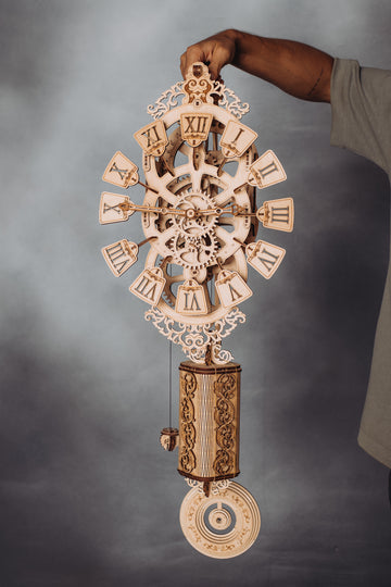 Complete WoodTrick Pendulum Clock houten wandklok met zichtbaar uurwerk, aandrijfgewicht en lange slinger in de hand