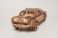 Een gedetailleerde houten modelauto van de WoodTrick Full-size Pickup Truck - Amerikaans Autopakket, gezien van linksachter met WOODTRICK en HEAVY op de achterklep, het ideale bouwpakket voor volwassenen tegen een witte achtergrond.
