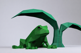 Groene geometrische kikker beschut onder twee grote bladeren als 3D-papiermodel