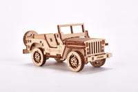 De WoodTrick Militaire SUV - Legerauto Bouwpakket is een gedetailleerd houten model van een klassieke militaire jeep met reservewiel, perfect voor fans van bouwpakketten. Van het merk WoodTrick, gefotografeerd op een effen witte achtergrond.