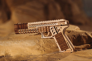 Complete WoodTrick Defenders Gun op een rotsachtige ondergrond met het houten pistoolmodel volledig in beeld