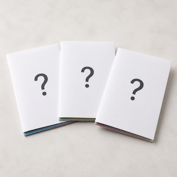 Drie gesloten papercraftpakketten met vraagtekens als illustratie van het verrassingspakket met drie papieren modellen
