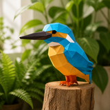 Zittende blauwe en oranje ijsvogel van papier op een stronk tussen groene planten