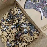 Een close-up van de Grijze Olifant Houten Puzzel (A3 formaat) - Majestueus Dier Figuurpuzzel van SlimSpul nederland b.v. laat kleurrijke, gedessineerde stukjes zien in een houten doosje - perfect als dierenfiguur legpuzzel voor volwassenen.