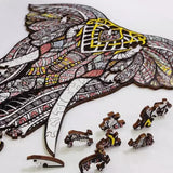 Een gedeeltelijk voltooide Grijze Olifant Houten Puzzel (A3 formaat) - Majestueus Dier Figuurpuzzel van SlimSpul nederland b.v. toont gedetailleerde zwarte, gele en rode ontwerpen. Diervormige stukjes, sommige lijken op kleine beestjes, liggen verspreid in de buurt.