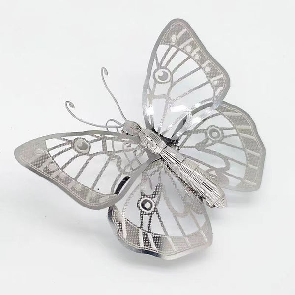 Het Vlinders Metalen Bouwpakket (Set van 2) van SlimSpul nederland b.v. heeft delicate zilvermetallic vlindermodellen met ingewikkelde, geometrische vleugelpatronen - perfect voor insectendecoratie, afgebeeld op een effen witte achtergrond.