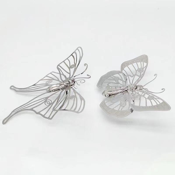 Het Vlinders Metalen Bouwpakket (Set van 2) van SlimSpul nederland b.v. bevat delicate, zilveren insectenmodellen met uitgesneden patronen, perfect als elegante vlinders decoratie voor elk kapsel.