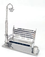 Het Parkbankje met Lantaarn Metalen Bouwpakket - Miniatuur Stadsgezicht van SlimSpul nederland b.v. is een elegant metalen bouwpakket met bankje, straatlantaarn en prullenbak op een trottoirbasis - perfect voor je eigen miniatuur stadsgezicht.