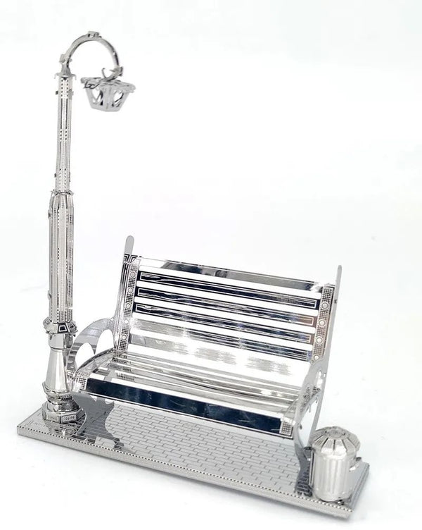 Het Parkbankje met Lantaarn Metalen Bouwpakket - Miniatuur Stadsgezicht van SlimSpul nederland b.v. is een elegant metalen bouwpakket met bankje, straatlantaarn en prullenbak op een trottoirbasis - perfect voor je eigen miniatuur stadsgezicht.