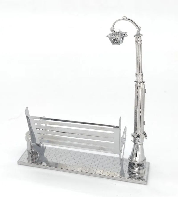 Het Parkbankje met Lantaarn Metalen Bouwpakket - Miniatuur Stadsgezicht van SlimSpul nederland b.v. is een klein metalen bouwpakket met een moderne parkbank en straatlantaarn op een voet van stoeptegels voor een stijlvol stadsgezicht.