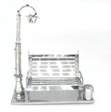 Het Parkbankje met Lantaarn Metalen Bouwpakket - Miniatuur Stadsgezicht van SlimSpul nederland b.v. is een klein metalen model met een parkbank, straatlantaarn en prullenbak op een betegelde voet, met reflecterende oppervlakken en fijne details.